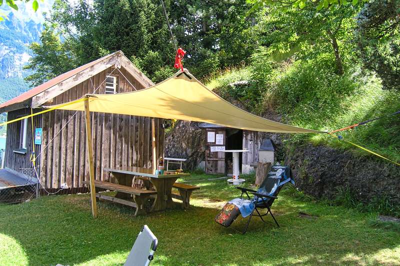 Clubhaus des TC Octopus Sarganserland mit Sitzplatz im Grünen und Sonnensegel am Walensee