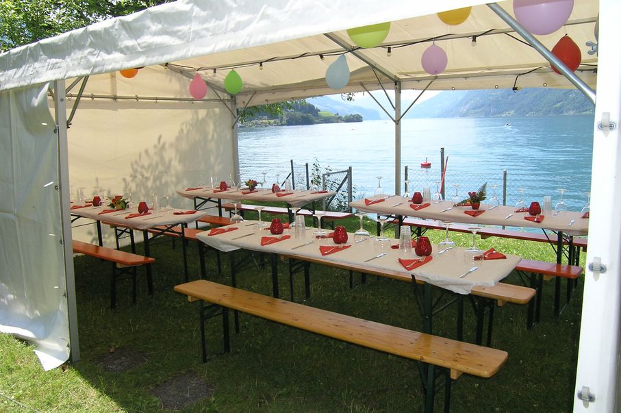 Festb&auml;nke dekoriert im Zelt auf dem Clubgel&auml;nde mit Blick auf den See